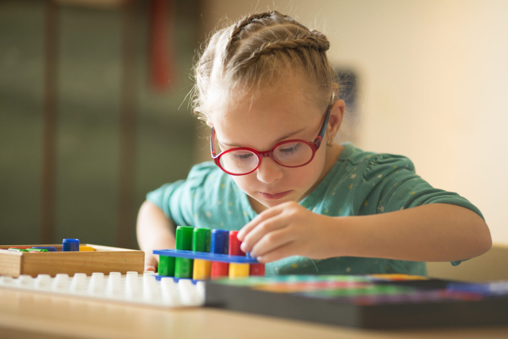 Smiling girl with red glasses playing with colorful educational toys.