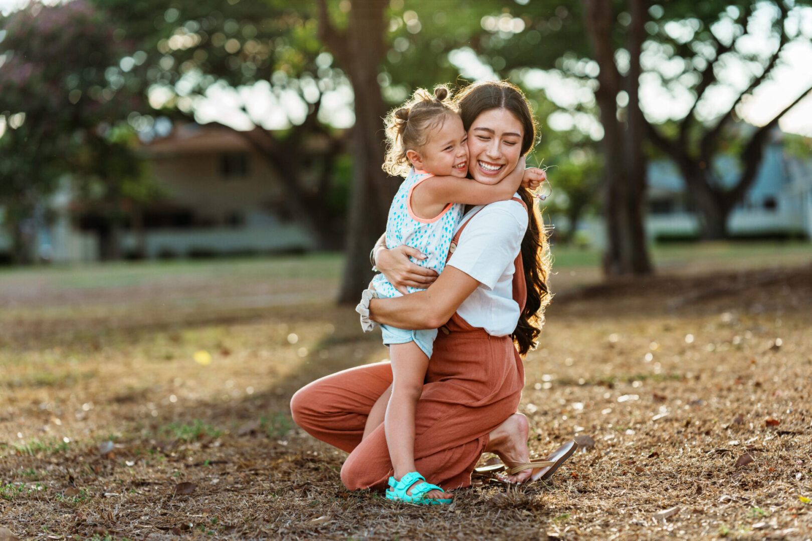 A joyful mother and child hugging outdoors in natural light.