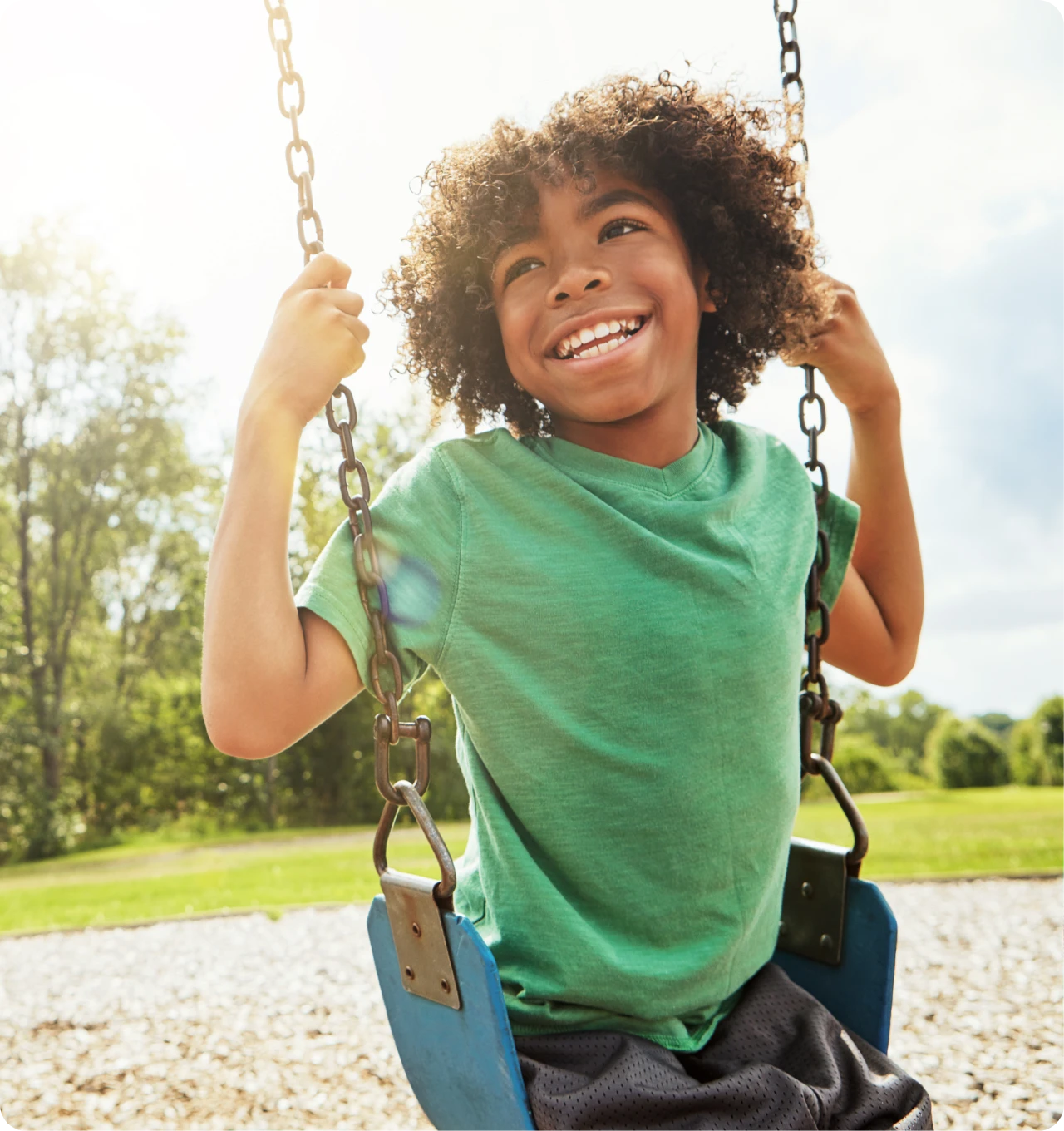 Child smiling on a swing outdoors.