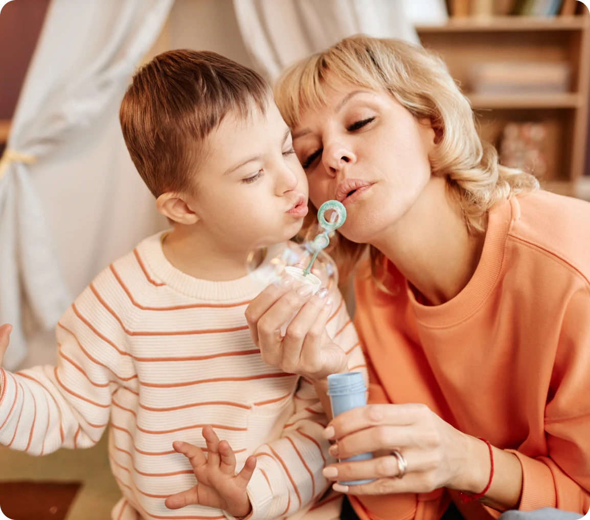 Mother and child blowing soap bubbles together.
