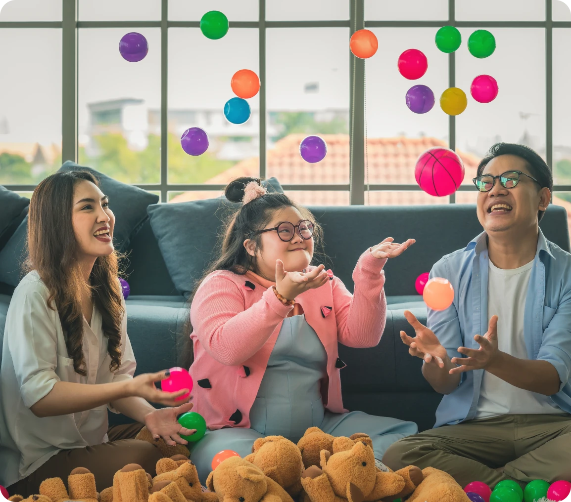 People joyfully playing with colorful balls indoors.